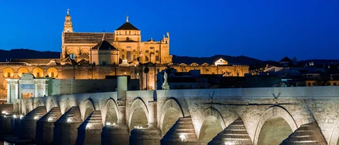 The Roman bridge over the Guadalquivir with the Mezquita-Catedral lit behind it at dusk, Córdoba