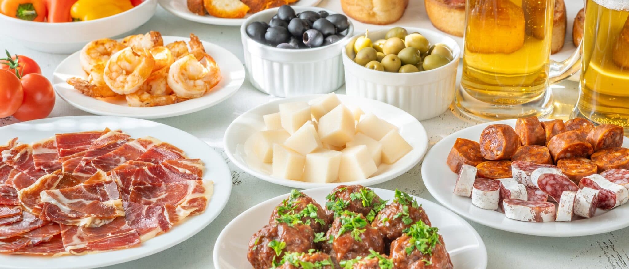 A spread of Spanish tapas with jamón, croquetas, olives and beer