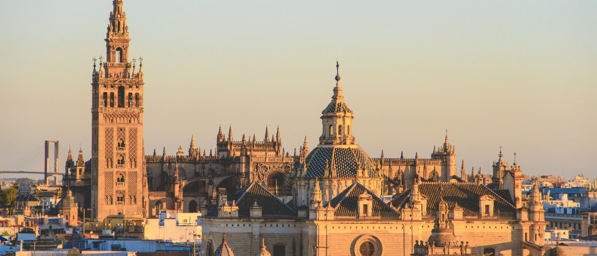 The Giralda tower and Seville Cathedral rising above the city rooftops at sunset