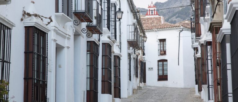 A whitewashed Andalusian street with mountains behind